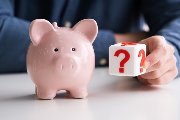 piggy bank facing forward while person holds a question block on the left of it