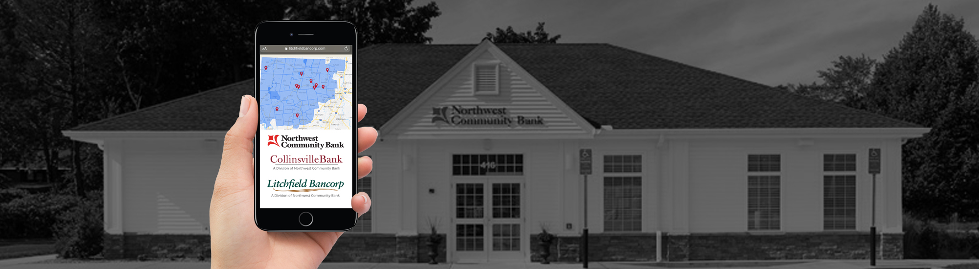 Hand holding an iPhone with Northwest Community Bank website loaded while standing in front of bank